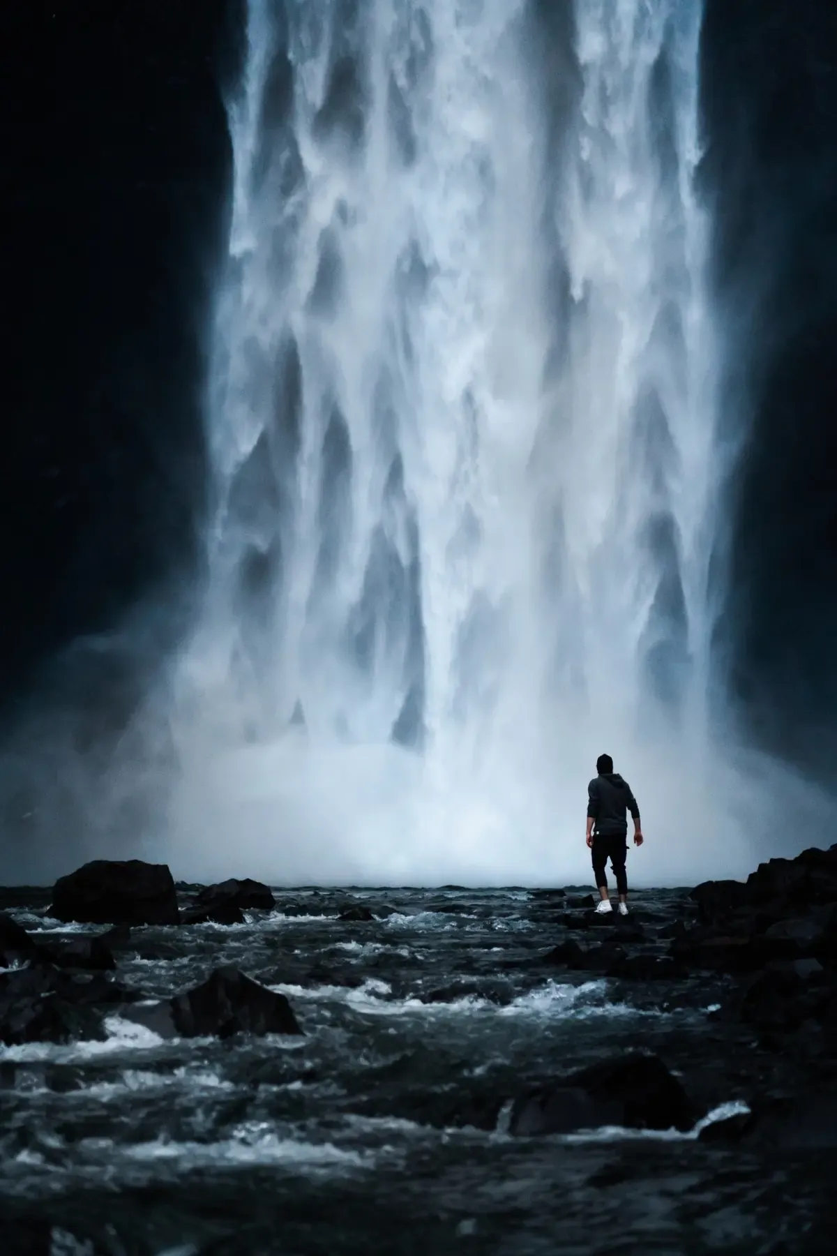 A lone figure before a waterfall