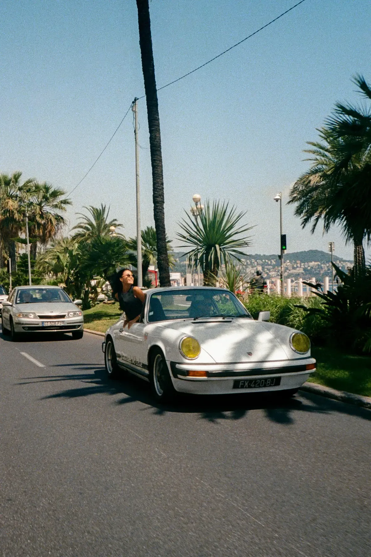 Classic white Porsche on a palm-lined road
