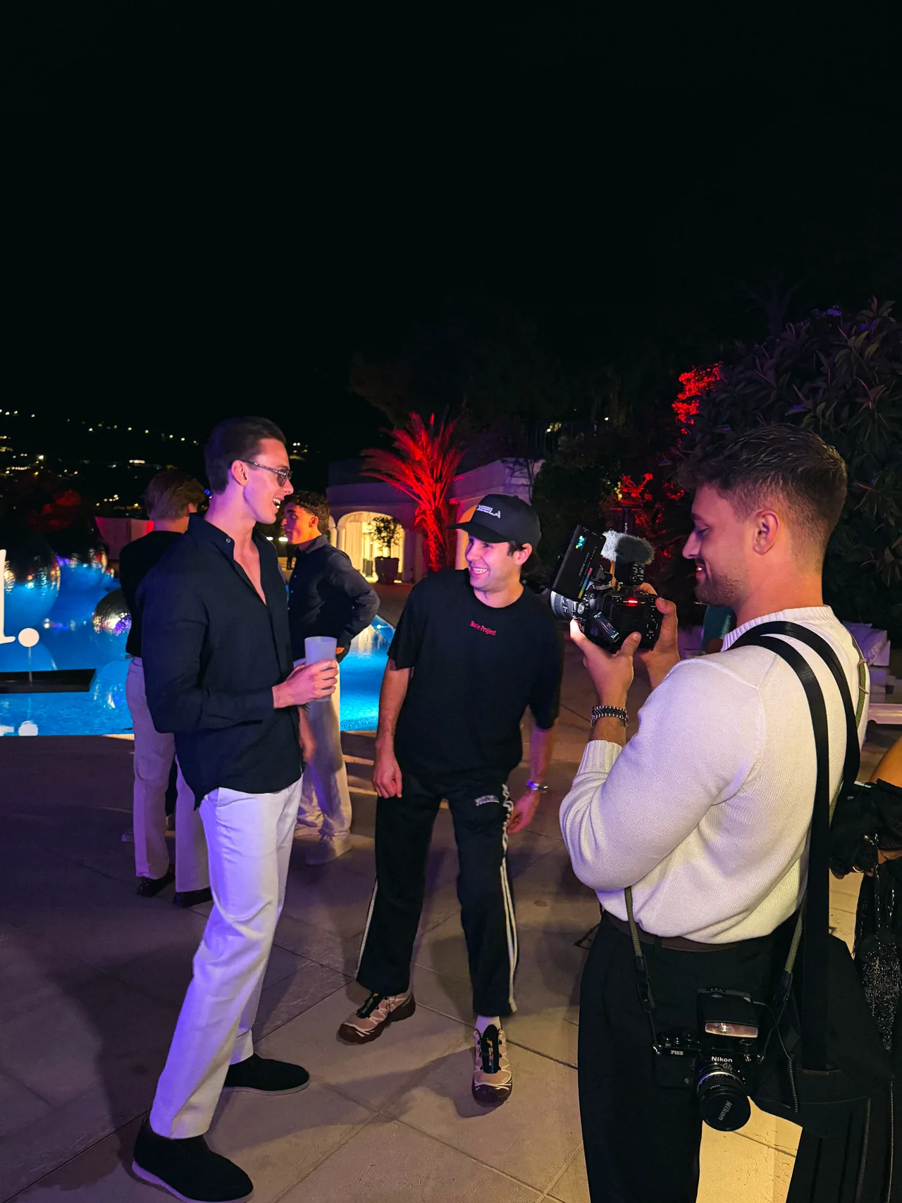 Filming a conversation beside a lit pool at a night event