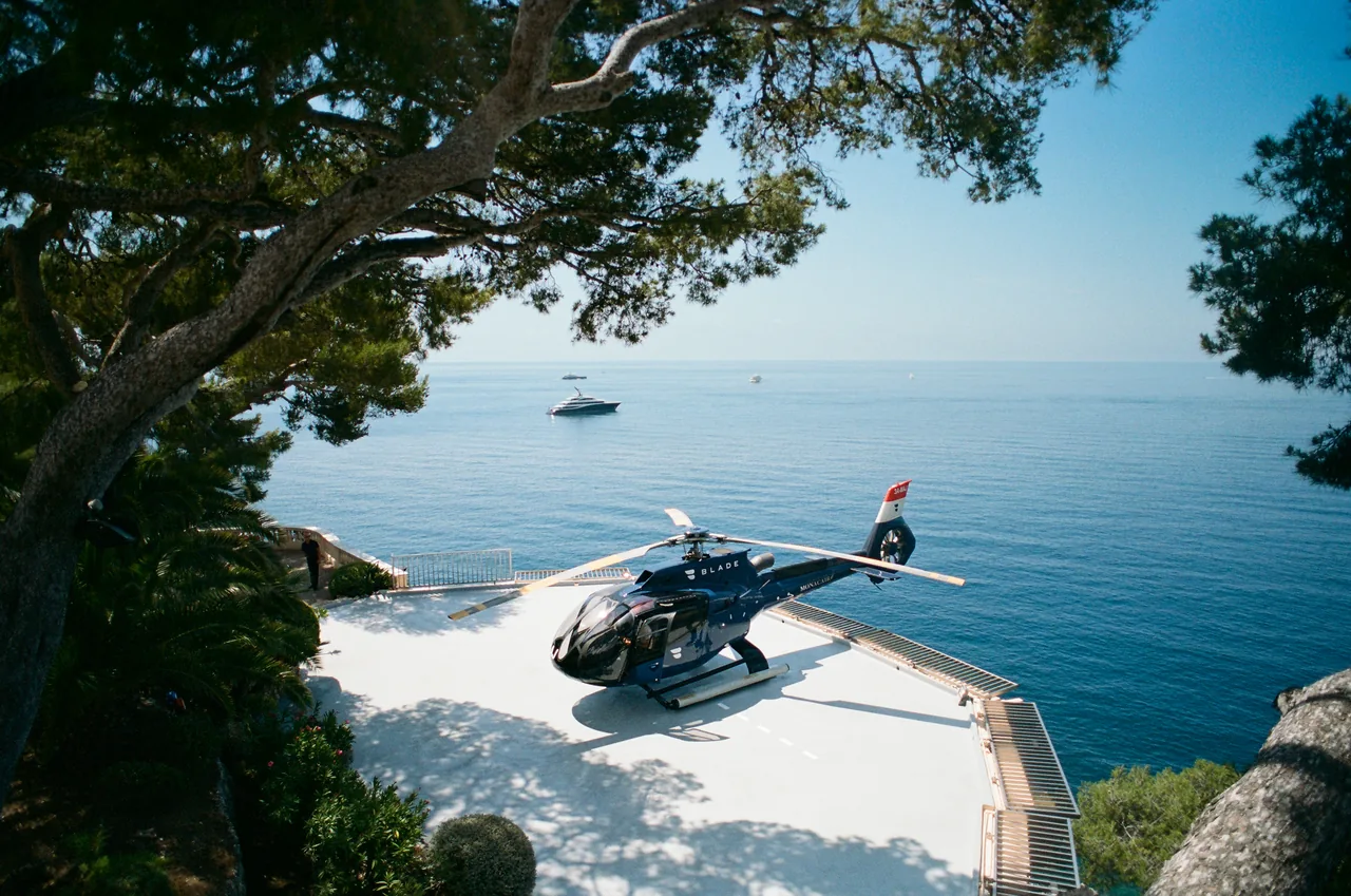 A helicopter on a cliffside helipad above the Mediterranean